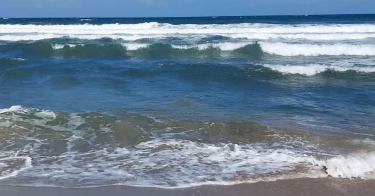 Тяло на жена е открито в морето край Несебър Морски вълни се разбиват на пясъчен плаж под синьо небе.